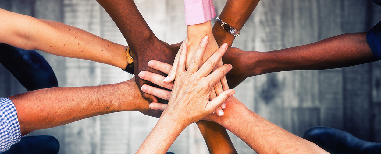 Several hands coming together in a team huddle. 